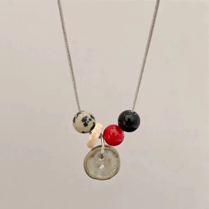 Detail of vintage beaded necklace with dalmatian stone and button pendant on snake chain