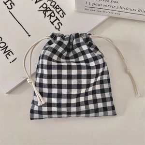 Close-up of a black and white gingham drawstring pouch on a minimalist desktop