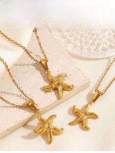 Détail de trois pendentifs étoile de mer dorés avec texture à pois sur pierre beige