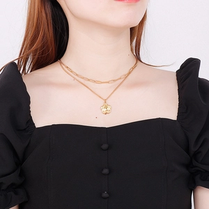 Close-up of double-layer gold necklace featuring paperclip chain and flower pendant
