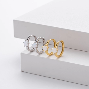 Polished silver and gold huggie earrings with round white opal stones on white steps
