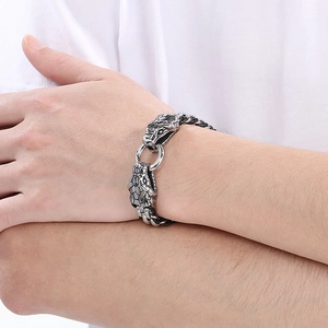 Détail des deux têtes de dragon argentées sur un bracelet en cuir tressé pour hommes