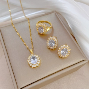Luxury gold jewelry set featuring oval crystal necklace, ring and earrings in a gift box