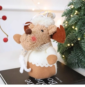 Detail of plush Christmas reindeer ornament with felt hat and hanging rope on a book