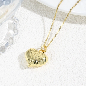 Detailed view of hollow heart pendant with 18k gold plated texture and delicate chain