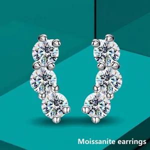 Three-stone moissanite stud earrings in silver curved setting with blue geometric background