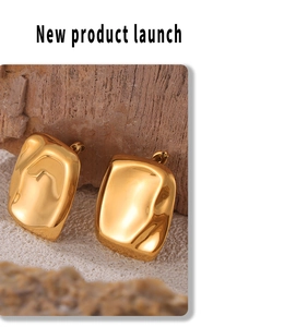 Detailed close-up of 3D gold rectangle earrings with a polished mirror finish on natural rock