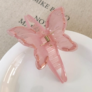 Detailed close-up of a pink ribbon butterfly hair claw clip with a glossy acrylic finish