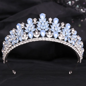 Detailed view of silver bridal tiara with light blue crystals on black fabric background