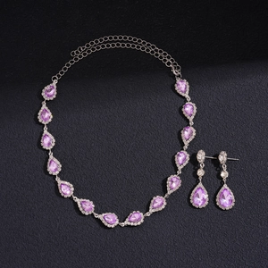 Détail macro du pendentif en cristal violet en forme de goutte et boucles d'oreilles argent