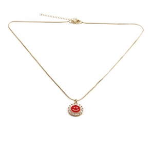 Detail of gold necklace with red enamel smiley pendant and crystal-encrusted rim