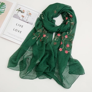 Detail of green chiffon scarf with delicate pink floral embroidery and soft texture