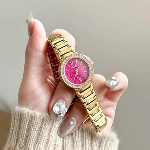 Montre dorée pour femme avec lunette en strass et cadran marbré rose au poignet