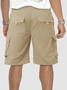 Detail view of khaki cargo shorts featuring elastic waist and rear flap pockets