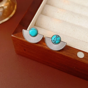 Close-up of vintage silver fan-shaped earrings featuring a turquoise stone inlay on wood