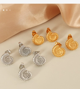 Macro detail of nautical spiral shell stud earrings in gold and silver finish