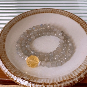 Detail of multi-layer beaded bracelet with grey moonstone and carved amber center piece