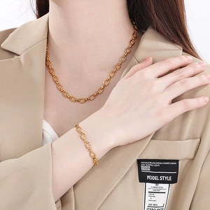 Ensemble collier et bracelet élégant en acier inoxydable doré porté par un mannequin