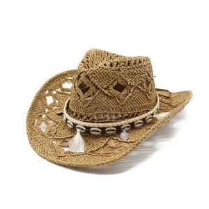 Detail of western straw cowboy hat with cutout weave, shell accents and cotton tassels