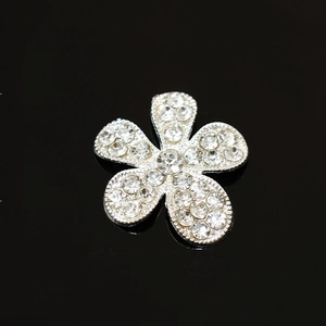 Détail macro d'une fleur à cinq pétales argentée avec strass sur fond noir brillant