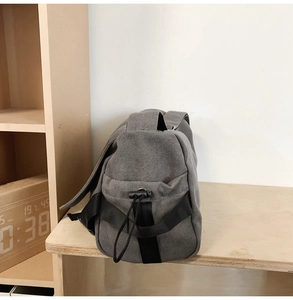 Side view of dark gray canvas messenger bag with adjustable drawstring and reinforcement straps