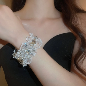 Gros plan d'un bracelet en dentelle blanche orné de strass brillants au poignet