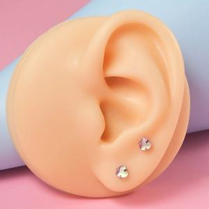 Vue macro de piercings à lèvres en forme de cœur pailleté sur un modèle d'oreille