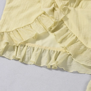 Detailed view of light yellow tube top featuring ruffled edges and textured vertical ribbing