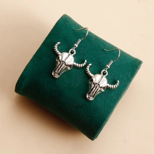 Vue détaillée de boucles d'oreilles crâne de taureau argentées sur un coussin en velours