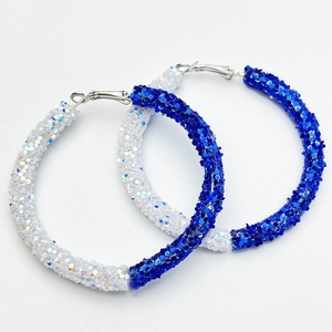 Detailed view of large C-shaped hoop earrings with blue and white shimmering sequins