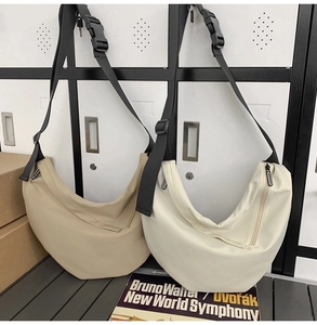 Detail view of khaki and off-white crescent crossbody bags with adjustable buckle straps