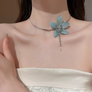 Close-up of blue glitter fabric flower pendant with silver tassel on snake chain necklace