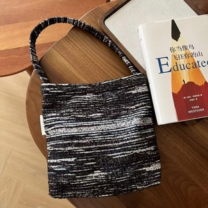 Retro black and white tweed knit handbag displayed at a 45-degree angle on a wooden table