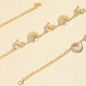 Detailed view of gold metal starfish and seashell beach body chains with lobster clasp