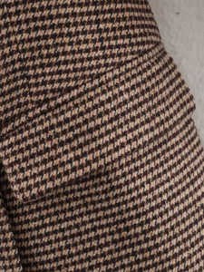 Close-up macro detail of classic brown houndstooth fabric texture on long coat blazer