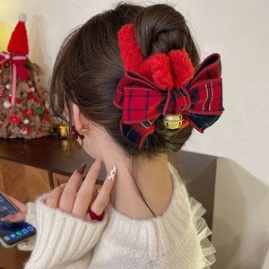 Red plaid Christmas hair claw with plush bow and gold bell on a female model