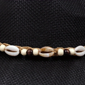 Detail eines Panamahut-Bandes mit Muscheln und Perlen auf schwarzem Leinengewebe