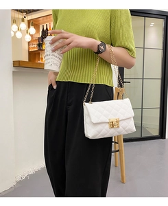 Detail of white quilted PU leather bag with golden chain strap and turn-lock closure