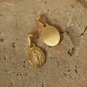 Macro detail of gold-plated titanium unicorn sun god pendant with Virgin Mary relief