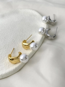 Détail de boucles d'oreilles élégantes en forme de C, dorées et argentées avec perles
