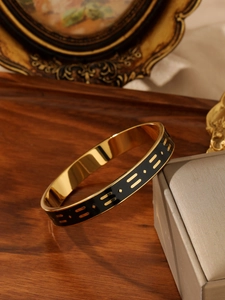 Detail view of Bohemian titanium steel bangle with gold and black enamel geometric patterns