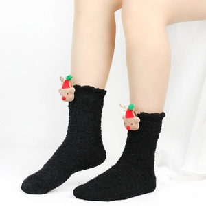 Detail von flauschigen schwarzen Korallenvlies-Socken mit süßem Rentier-Puppen-Anhänger