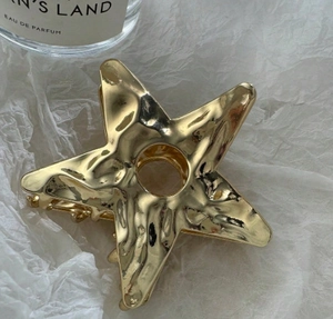 Detailed view of large gold hollow star hair claw with textured metallic finish