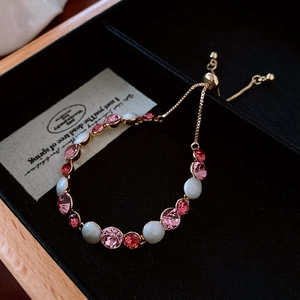 Detail of adjustable gold bracelet with pink rhinestones and pearls in a black jewelry box