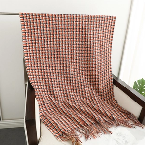 Detailed view of orange and navy plaid scarf with soft fringe edges on a chair