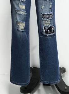 Detail der dunkelblauen Jeans mit Totenkopf-Patch, schwarzen Pailletten und Löchern