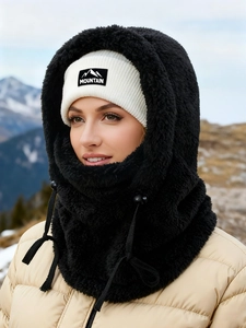 Detail of warm black faux fur balaclava and white knit beanie with Mountain logo patch