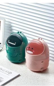 Close-up of cute dinosaur mini desktop trash cans with flip lids in pink and green