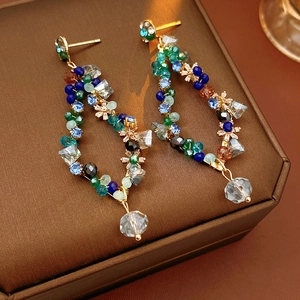 Detail of vintage diamond tassel earrings with multicolor beads and gold finish