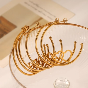 Polished gold stainless steel hoop earrings with heart charms on glass rim